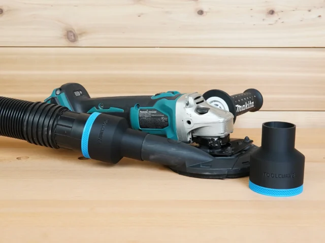 Black 2-1/2 inch ToolCurve hose adapter on Makita XAG04 grinder shroud, second adapter shown beside it
