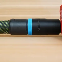 Black ToolCurve hose adapter with blue band attached to braided hose, connected to red Milwaukee planer port