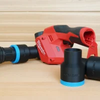 Black ToolCurve 1-7/8 inch hose adapters with blue rings, one joined to a vac hose beside a red Milwaukee M12 planer