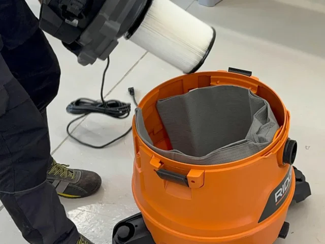 Orange Ridgid shop-vac with gray reusable dust bag installed inside, shown from above with power cord and filter cartridge visible nearby