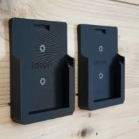 Two black plastic battery mounts labeled Ridgid mounted on a light wood wall, each with a rectangular opening and two screw holes
