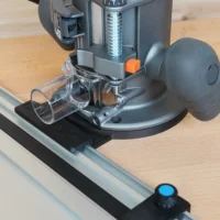 Guide rail adapter mounted on Ridgid 2 HP router base, attached to aluminum track saw rail on wooden workbench