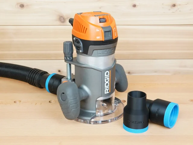 Black ToolCurve 1-7/8 in. hose adapter on a Ridgid 2 HP fixed base router's dust port, spare adapter beside it