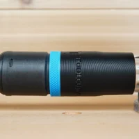 Black hose adapter with blue band installed on Ridgid router, braided hose attached to left end, clear connector on right