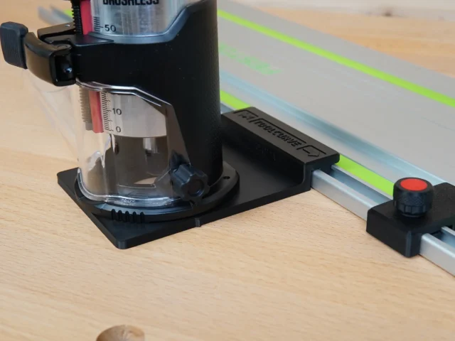 Black plastic guide rail adapter mounted on SKIL 20v trim router, positioned on a Festool track saw rail with bright green stripe