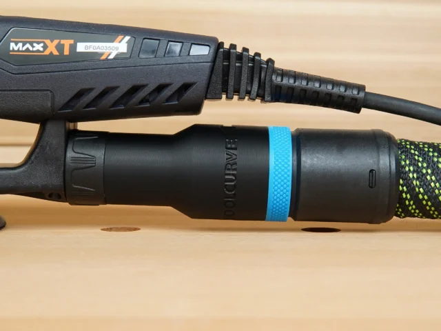 Black hose adapter with blue band attached to MAXXT sander dust port, showing threaded connection and braided hose