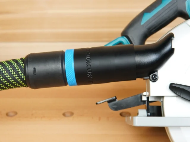 Black hose adapter with blue band attached to Makita 36v cordless circular saw dust port, next to Festool hose
