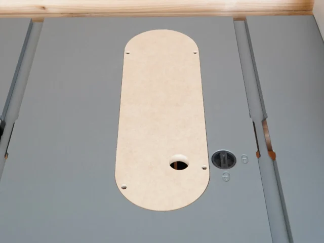 Cream MDF zero clearance insert installed in a Craftsman 10-inch table saw top, showing oval shape with center blade slot and mounting holes