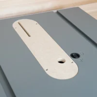 Cream-colored zero clearance insert for Hercules 10" table saw, installed on gray table saw top, showing central blade slot and mounting holes