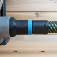 Hose adapter attached to Hercules table saw dust port, showing threaded connection with blue band and braided hose