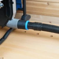 Black hose adapter with blue ring joining a 1-7/8 inch shop vac hose to the Hercules table saw rear dust port