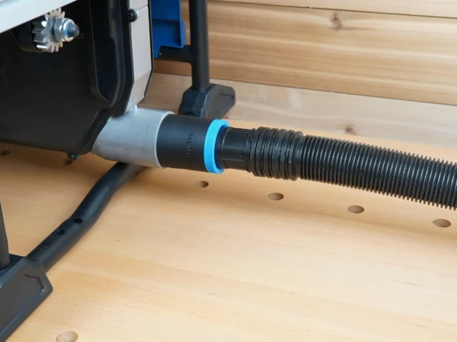 Black hose adapter with blue ring joining a 1-7/8 inch shop vac hose to the Hercules table saw rear dust port