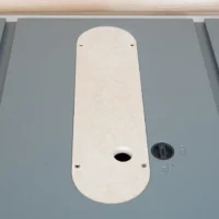 White MDF zero clearance insert for Hercules table saw, mounted on saw table with offset screws visible