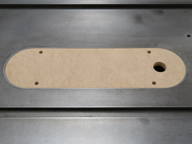 MDF zero clearance insert for Delta Unisaw X5 with four mounting holes and central blade slot, top view