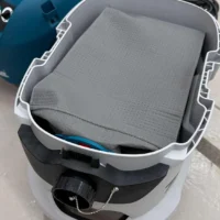 Gray reusable dust bag installed in a white and black Makita VC4210 dust extractor, viewed from above with the bag's perforated surface visible