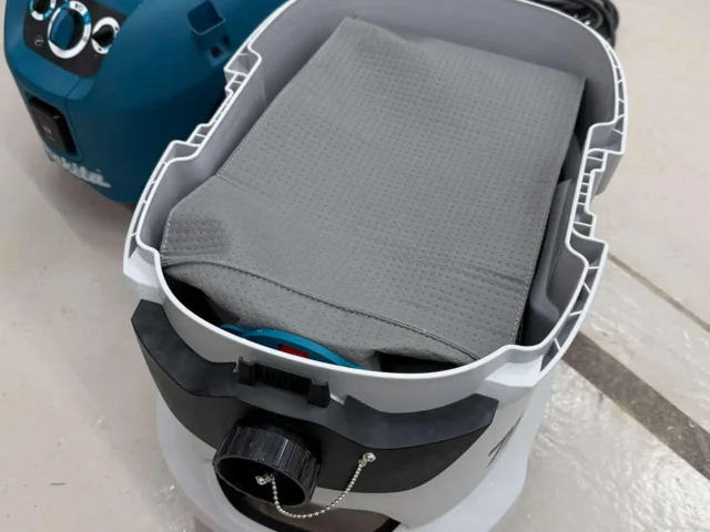 Gray reusable dust bag installed in a white and black Makita VC4210 dust extractor, viewed from above with the bag's perforated surface visible