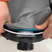 Gray reusable dust bag being installed on a Makita VC4210 dust extractor, with blue trim ring visible at the connection point