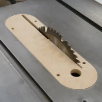 MDF zero clearance insert seated in a Delta Unisaw X5 table saw with the blade raised through the slot