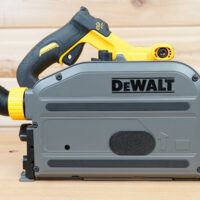 Black track saw dust cover installed on a DeWalt track saw, side view with dust hose port and yellow collar at left.