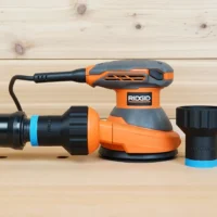 Black 1-1/4 inch hose adapter with blue band shown alone and fitted between orange hose and Ridgid 5 in. sander