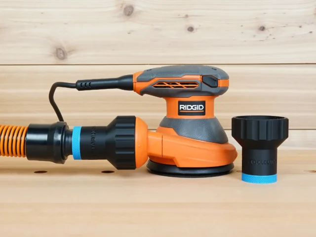 Black 1-1/4 inch hose adapter with blue band shown alone and fitted between orange hose and Ridgid 5 in. sander