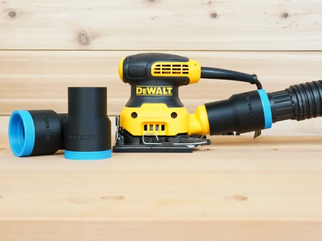 Black 1-7/8 inch ToolCurve hose adapter with blue rings, one installed on a DeWalt palm sander dust port