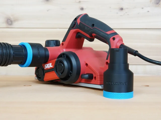 Black ToolCurve 1-7/8 in hose adapter with blue ring on red SKIL planer port, second adapter beside it