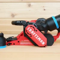 Black ToolCurve 2-1/2 inch hose adapter with blue band beside a Craftsman belt sander, second adapter on its dust port