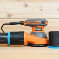 Black ToolCurve 2-1/2 inch hose adapter with blue band joining a vacuum hose to a Ridgid 5 in. sander, second adapter alongside