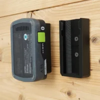 Two black battery holder mounts screwed to a wood wall, one holding a Festool 18V 4.0 Ah battery