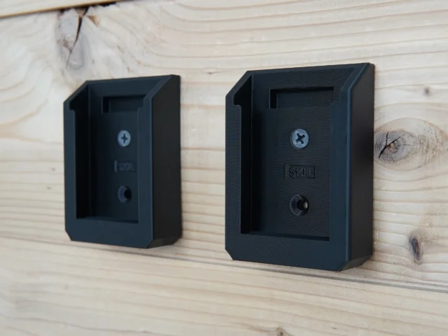Two black plastic battery mounts for SKIL 20v PWRCORE batteries mounted on light wood, each with a Phillips screw hole and mounting port