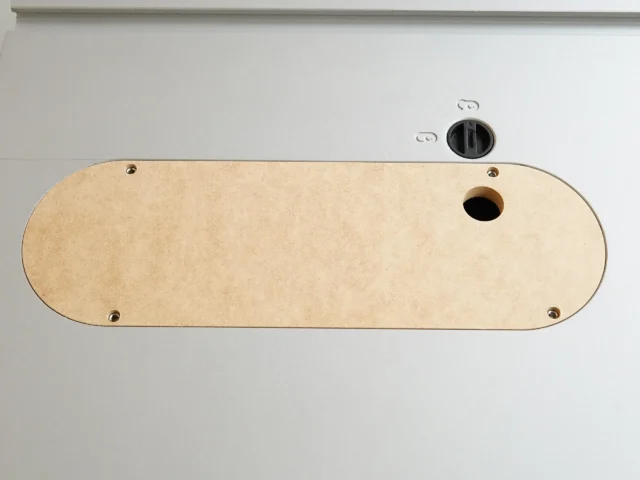 Light wood zero clearance insert for Kobalt table saw, mounted on saw top with four brass screws and one center hole for blade access