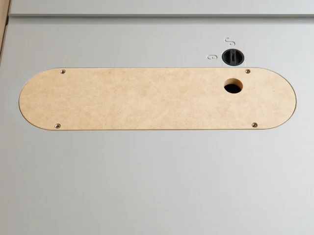 Beige MDF zero clearance insert for Kobalt 10-inch table saw, viewed from above, with four mounting holes and one centered blade opening