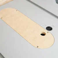 Light tan MDF zero clearance insert for Kobalt 10-inch table saw, with one oval cutout and mounting holes, set in a white table saw throat