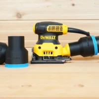 Black ToolCurve 2-1/2 inch hose adapter with blue trim installed on a DeWalt palm sander, second adapter beside it