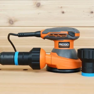 Black hose adapter with blue band joining a vacuum hose to a Ridgid 5 in. sander, second adapter alongside