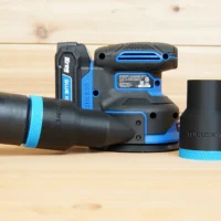 Black 36mm ToolCurve hose adapter with blue band joining a vacuum hose to a Kreg random orbit sander, second adapter beside it