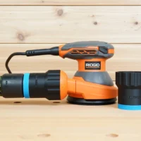 Black 36mm ToolCurve hose adapter with blue ring shown beside a Ridgid 5 in. sander and attached to a hose