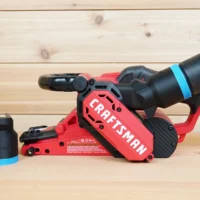 Black 36mm ToolCurve hose adapter with blue band beside a Craftsman belt sander with hose connected