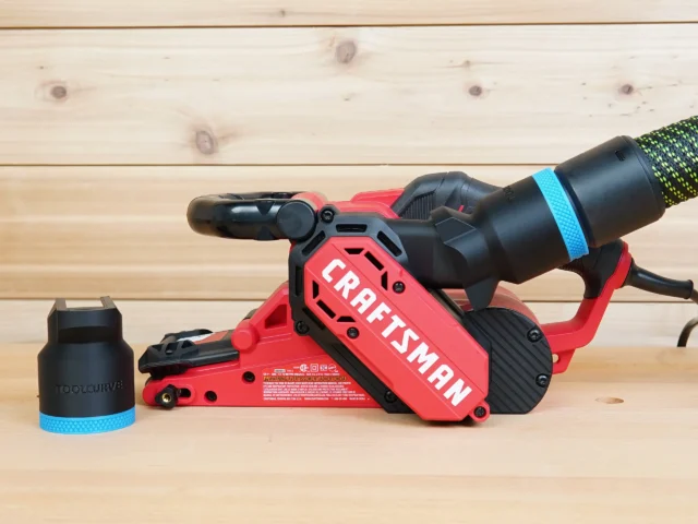 Black 36mm ToolCurve hose adapter with blue band beside a Craftsman belt sander with hose connected
