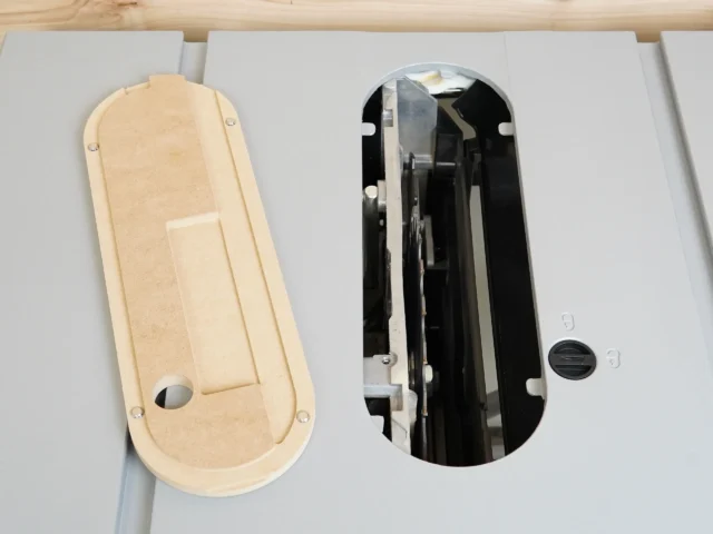 Cream-colored MDF zero clearance insert shown front and back, with mounting holes and rounded ends, next to black metal insert assembly for Kobalt 10″ table saw.