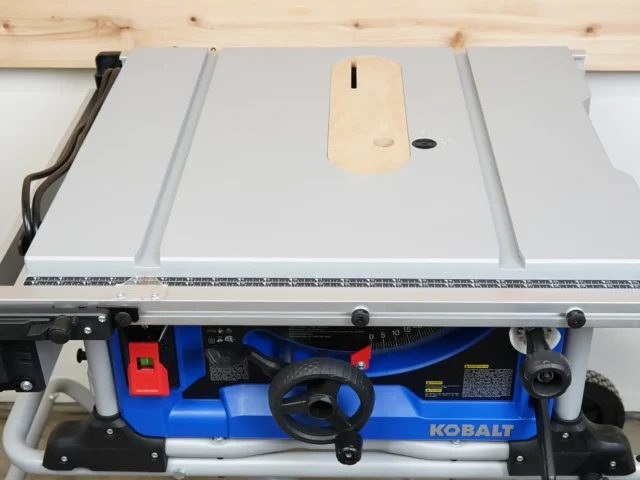 Zero clearance insert in light wood mounted on Kobalt table saw, showing slot for blade and adjustment holes