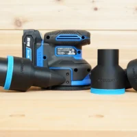 Black and blue 2-1/2 inch ToolCurve hose adapter fitted to a Kreg random orbit sander, with two spare adapters beside it