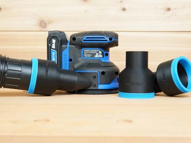 Black and blue 2-1/2 inch ToolCurve hose adapter fitted to a Kreg random orbit sander, with two spare adapters beside it