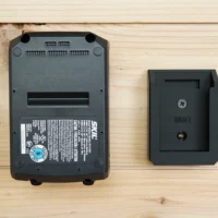 Small black wall mount with recessed slot, shown next to a SKIL 20v PWRCORE battery for size comparison
