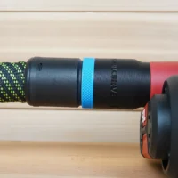 Black hose adapter with blue band mounted on a patterned hose, connected to a red SKIL planer on a wooden surface
