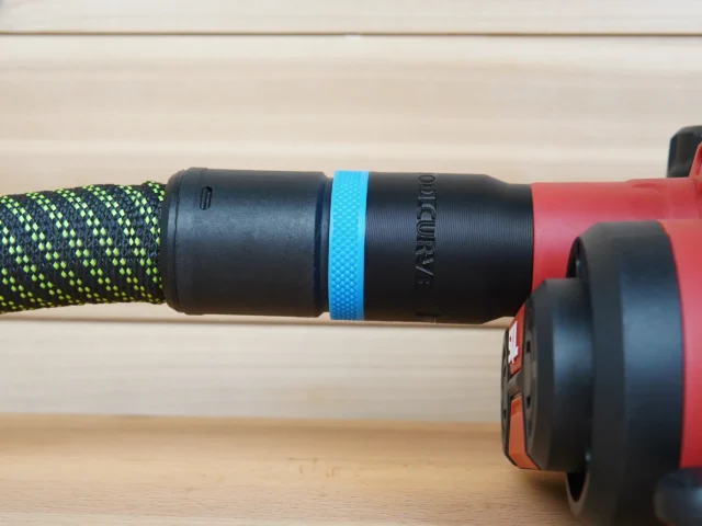 Black hose adapter with blue band mounted on a patterned hose, connected to a red SKIL planer on a wooden surface