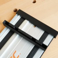 Black PETG protective caps fitted over both ends of a PowerTec aluminum guide rail on light wood surface