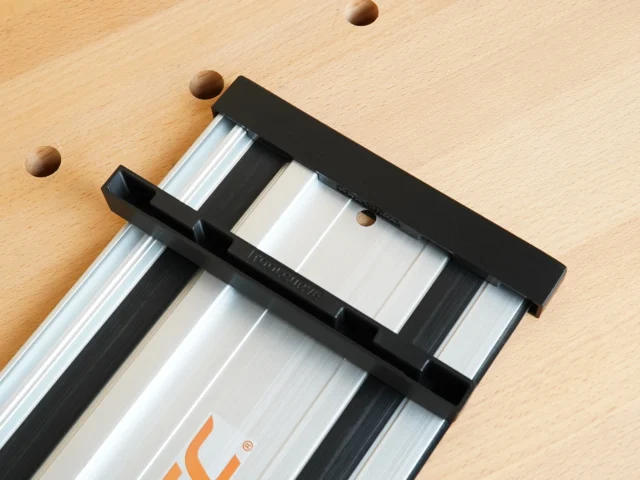 Black PETG protective caps fitted over both ends of a PowerTec aluminum guide rail on light wood surface