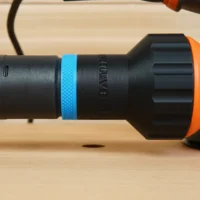 Black plastic hose adapter with blue grip band attached to Ridgid 5-inch sander's rear dust port, orange tool body visible